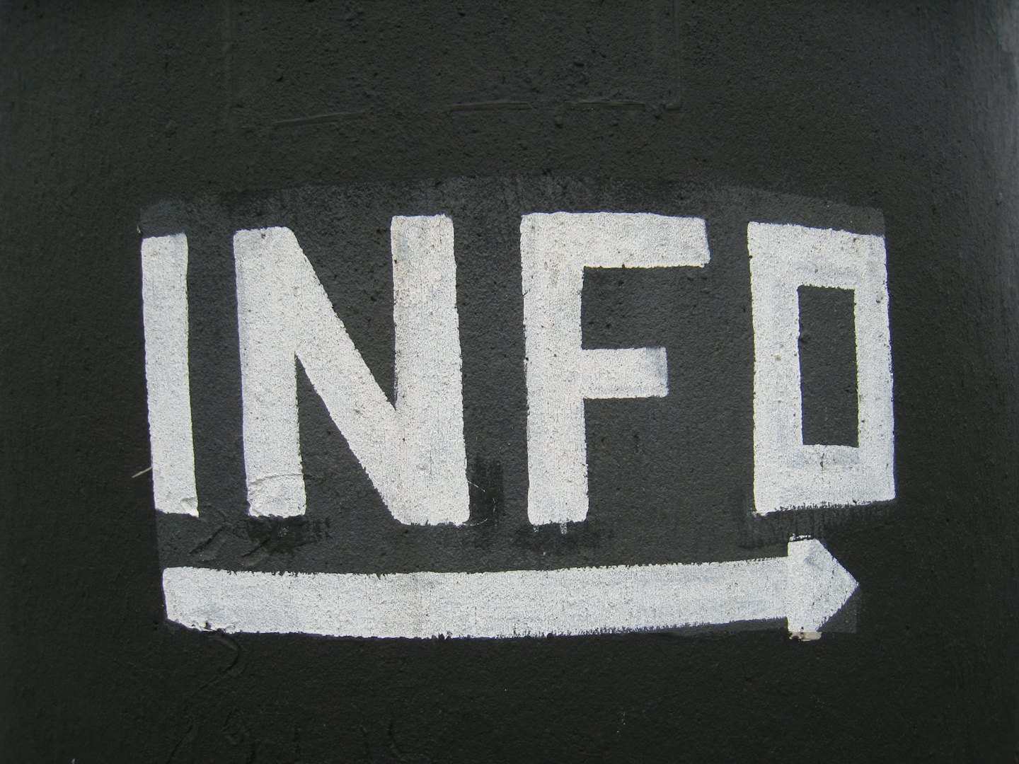 White text reads INFO with a white arrow pointing right on rough black surface.