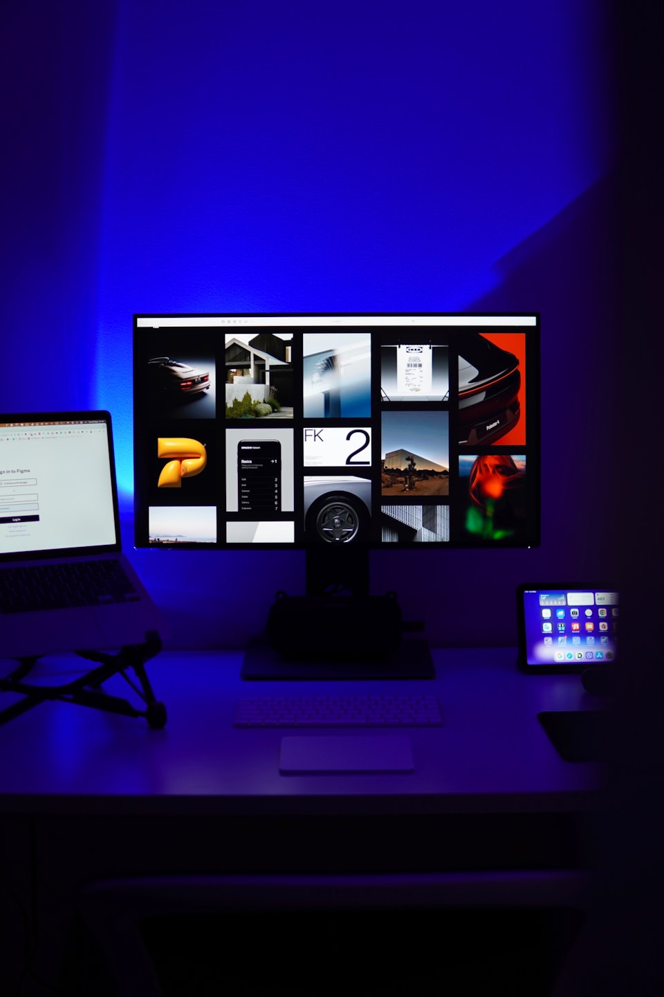 Modern desk setup featuring a monitor, laptop, and tablet.
